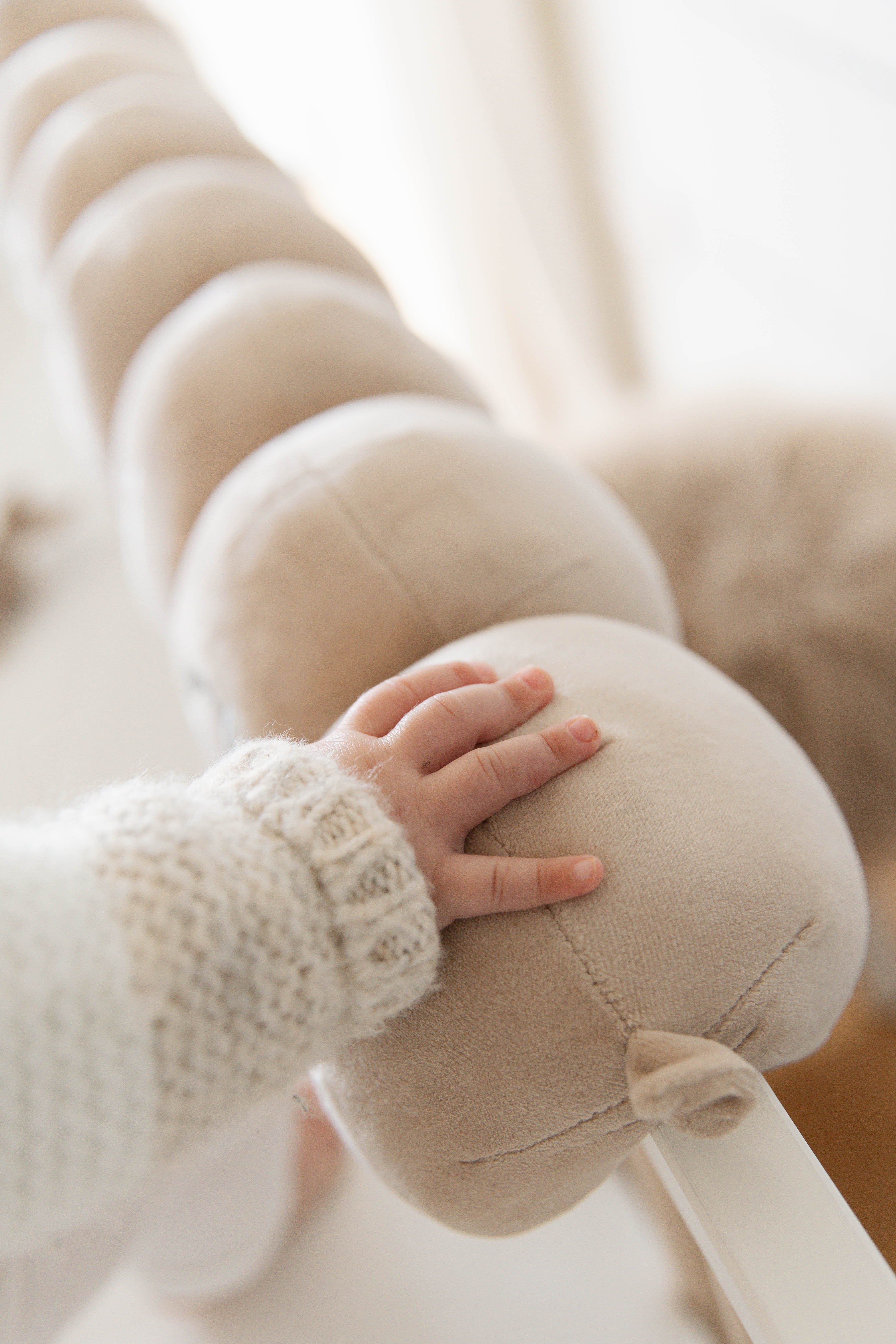 A baby’s hand resting on the soft plush surface of a Cotterpillar